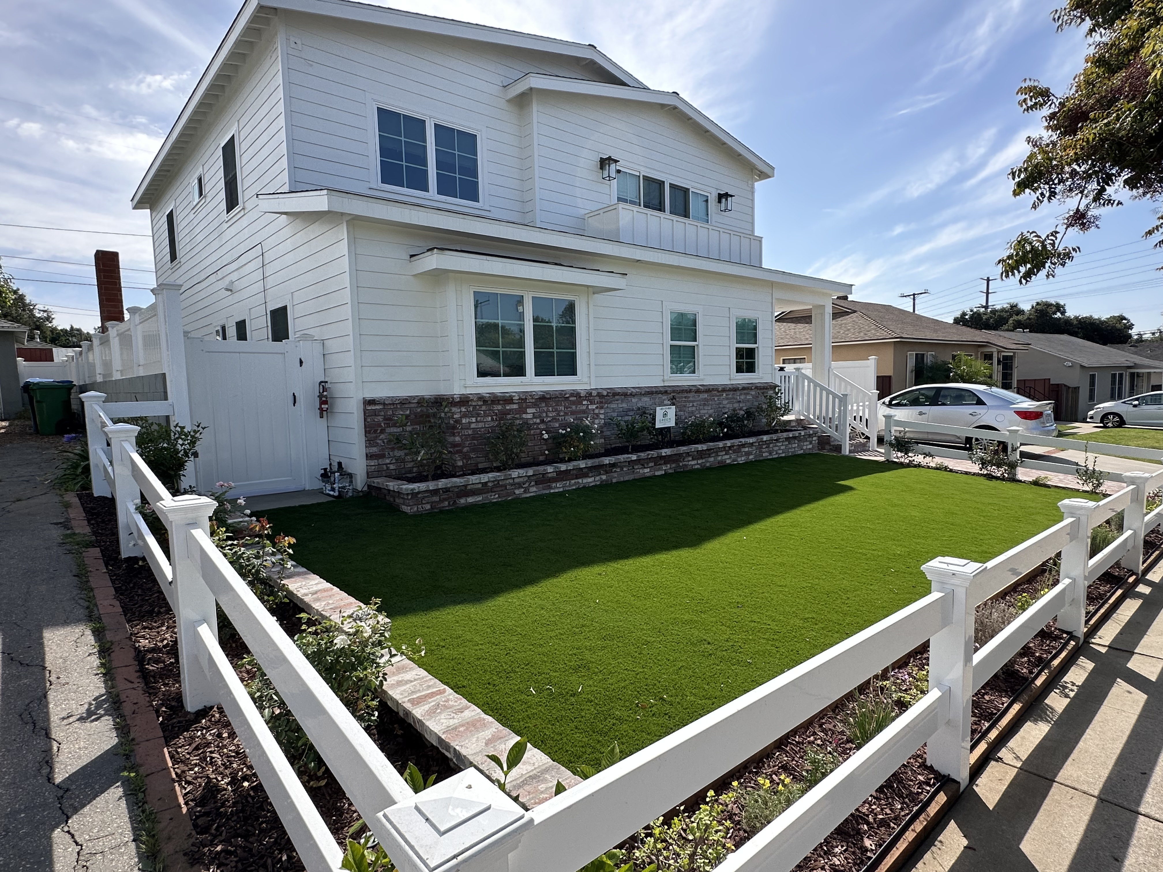 Turf layout in a front yard with a white fence